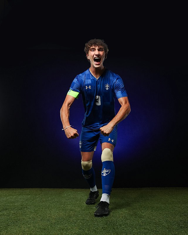 teenage boy soccer player in blue jersey poses intensely for photoday